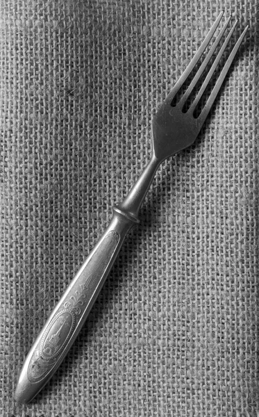 Old vintage fork on a linen napkin. Top view. Black and white photo