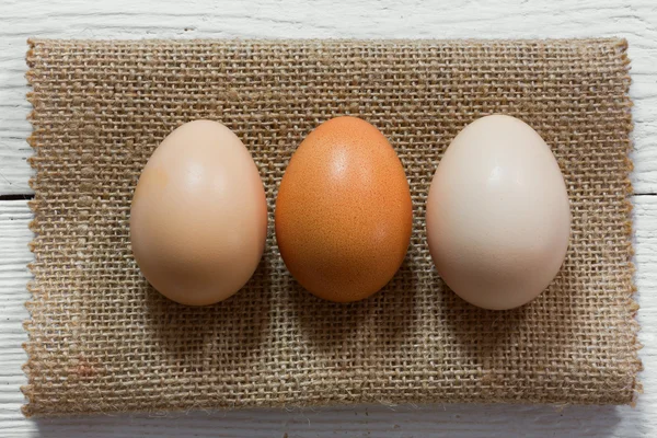 Three raw eggs in their shells lined up in a row on the matting, Close-up, top view