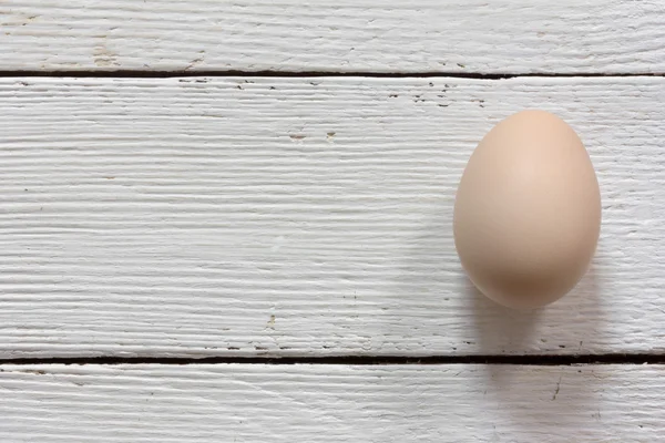Pink raw chicken egg in shell on white wooden boards. Copy space. Free space for text, Close-up, top view