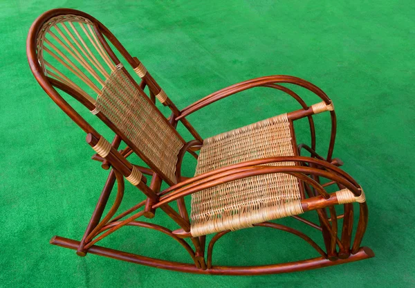 Rocking chair made from natural wood and wicker on a green background, side view