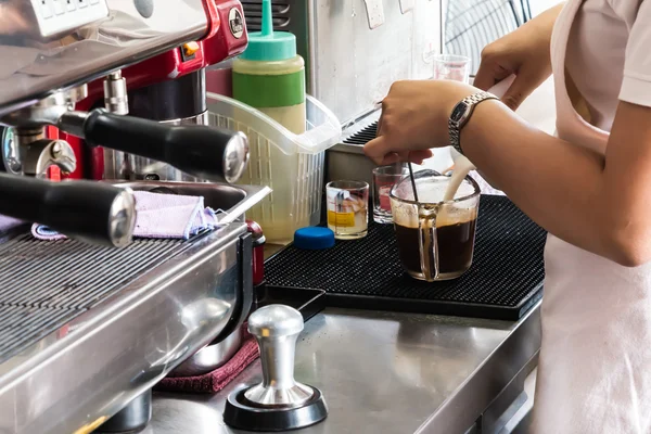 Coffee shop worker steams milk for a hot coffee
