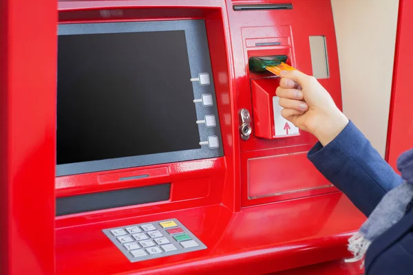 Woman inserting credit card into ATM to withdraw money