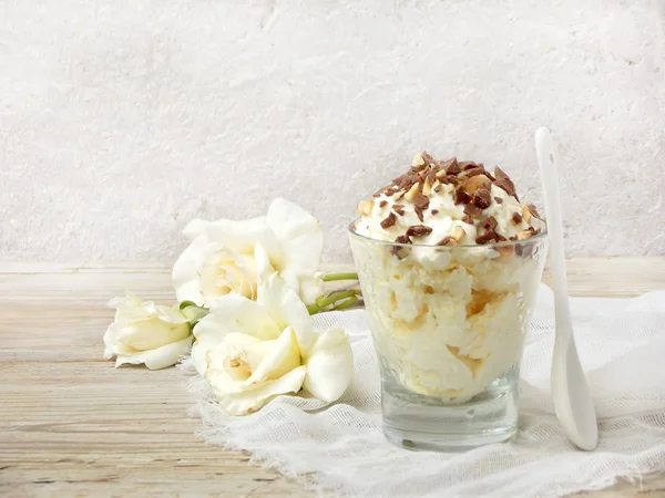 Homemade butter or lemon ice cream sprinkled with nuts and chocolate in a glass on a light wooden background