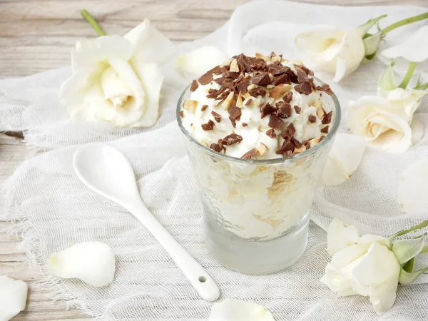 Homemade butter or lemon ice cream sprinkled with nuts and chocolate in a glass on a light wooden background