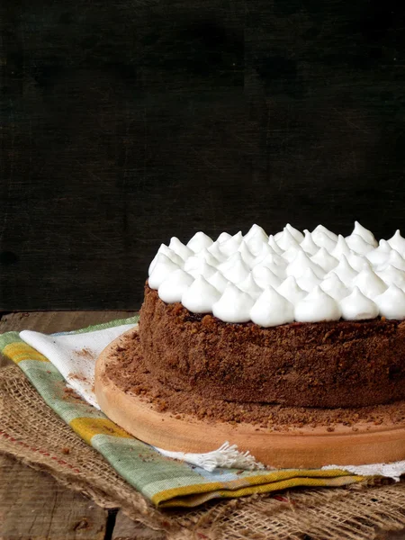 Truffle chocolate cake with prune jam covered with meringue