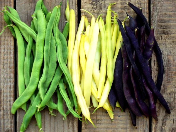 Fresh green, yellow and purple green beans, asparagus on a wooden background