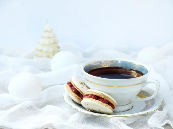 Cup of espresso coffee, French macaroons dessert on light background. Christmas and New Year cookies