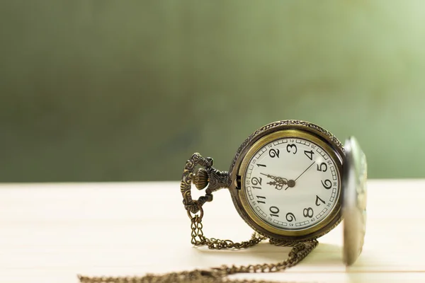 Antique clock on the wooden floor and green wall Background.