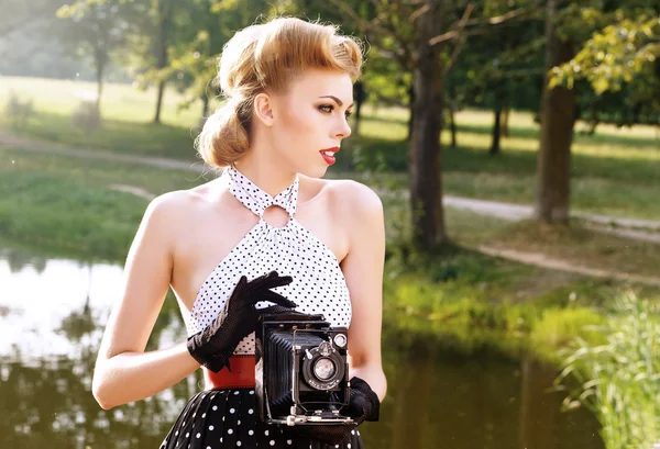 Beautiful woman with retro camera in the jungle.