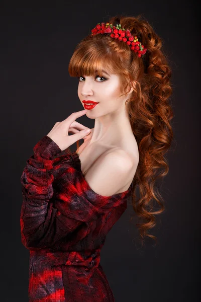 Sexy beautiful redhead girl with long curly hair and a red dress.hair ornament.red lips.
