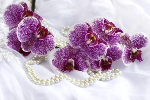 Orchid flowers and pearls on a wedding dress.