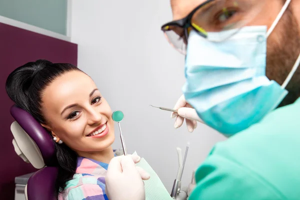 Woman sitting in dental chair while doctor examining her teeth