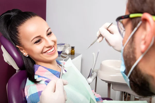 Woman sitting in dental chair while doctor examining her teeth