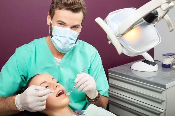 Male dentist examines mouth of woman on the dentist\'s chair