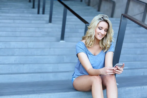 Girl student chatting on mobile phone and sitting on stairs