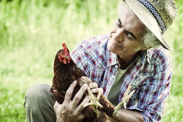 Smiling farmer holding a chicken