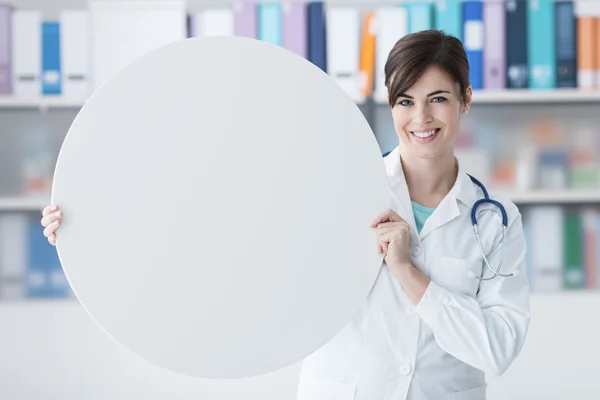 Smiling doctor holding a round sign