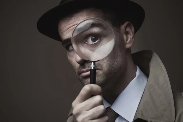 Vintage detective looking through a magnifier