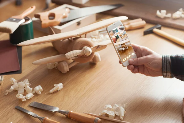 Man photographing his handmade wooden toy