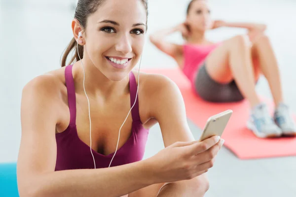 Young woman listening to music at the gym
