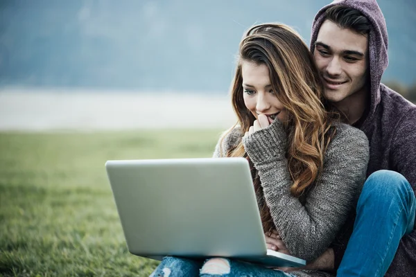 Playful couple using a laptop in nature