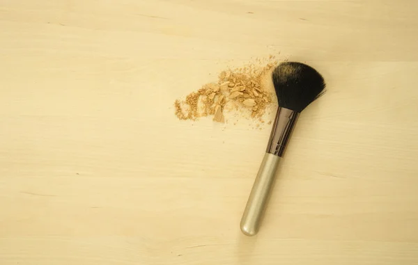 Face brush with skin powder on wood background