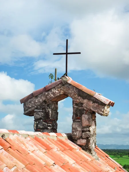 The tile roof of the bell tower with the cross