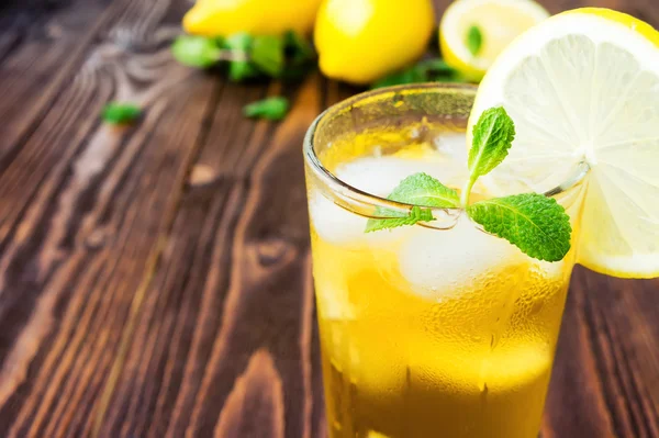 Two glasses of ice tea with ice-cubes on wooden table