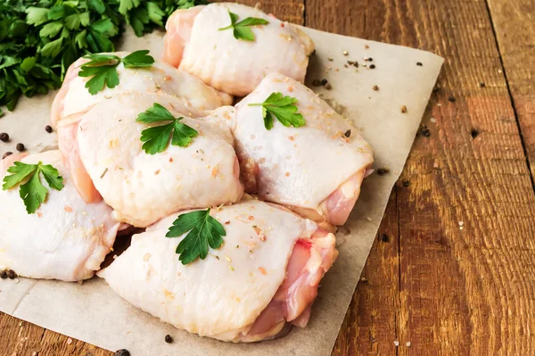 Raw chicken thighs with parsley on wooden table