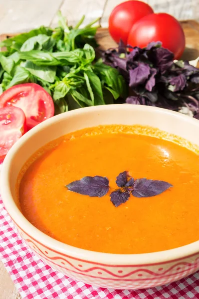 Fresh tomato soup with basil and tomatoes on wooden table