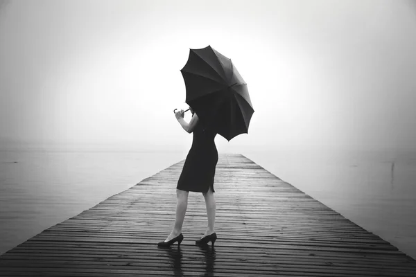 Woman with black umbrella looking infinity in a surreal place