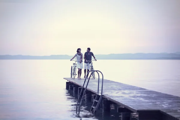 Couple in love pushing bike on a boardwalk at the lake