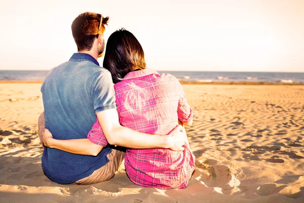 Sweet Couple Sitting on Sand at the Beach at sunset