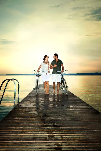 Couple in love pushing bike on a boardwalk at the lake