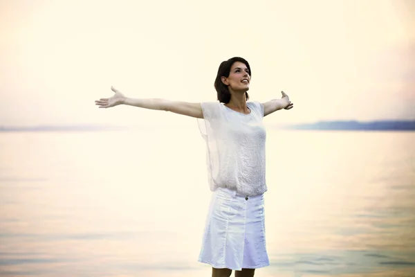 Happy woman taking a deep breath at the sunset