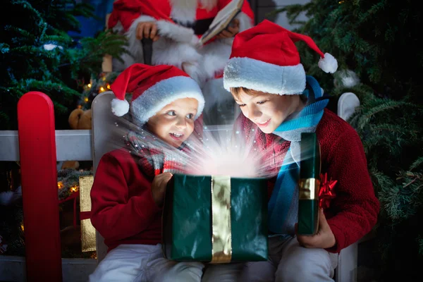 Two children opening Christmas gift with rays of light