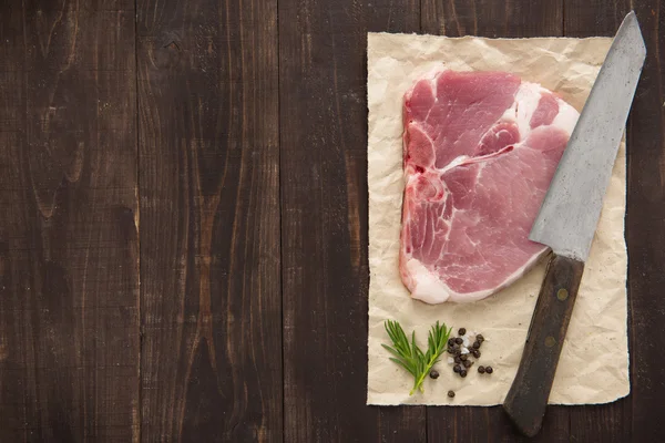 Raw pork chop steak and cleaver on wooden background
