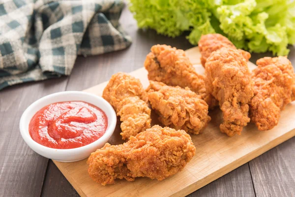Fried chicken drumstick and vegetables on wooden background