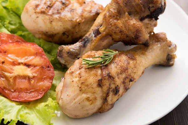 Grilled chicken drumstick and vegetable on white dish