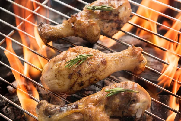 Chicken drumsticks grilling over flames on a barbecue