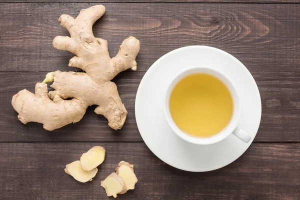 Ginger tea and ginger on the wooden background.