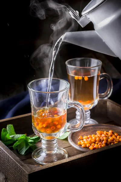 Hot tea flowing in glass cup with berries.