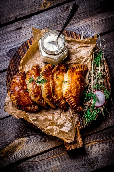 Fish pies and sour cream on a wooden chopping board, restaurant giving. Style rustic.