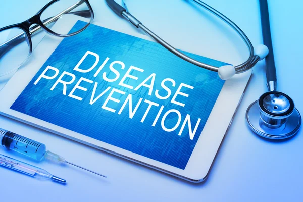 Disease prevention word on tablet screen with medical equipment on background