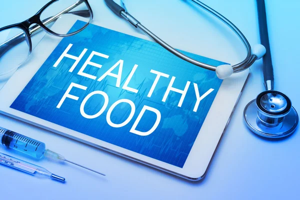 Healthy Food word on tablet screen with medical equipment on background