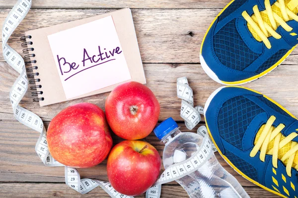 Sport shoes, apples, bottle of water, measuring tape and words \