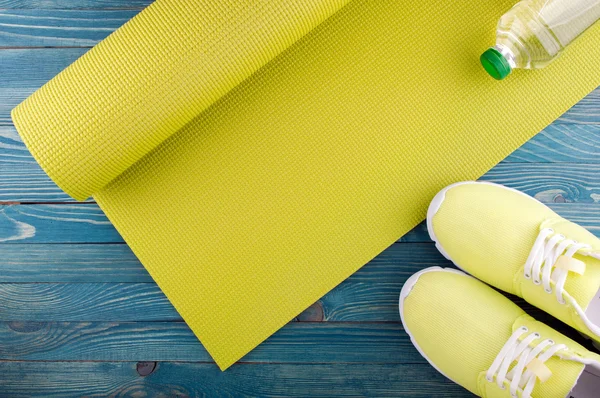 Healthy lifestyle background. Yoga mat, sport shoes, bottle of water on wooden background. Concept healthy and sport life
