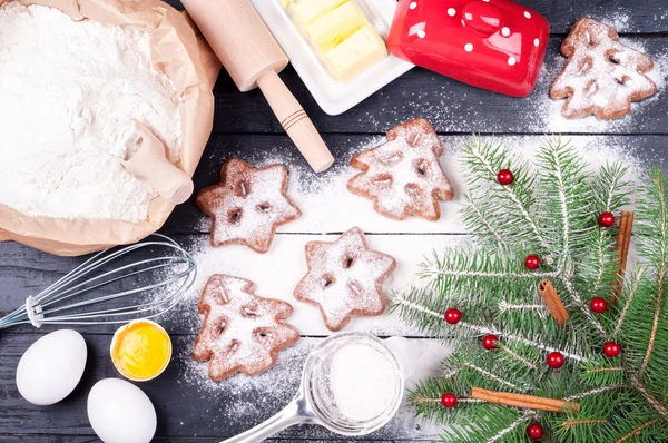 Ingredients for cooking Christmas baking with flour, eggs, butter and kitchen utensils - rolling pin and whisk. Homemade baked Christmas cookies on wooden background