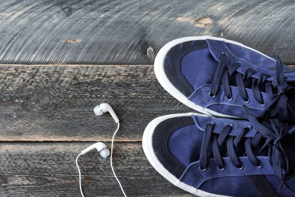 Sneakers and earphones on old wooden background