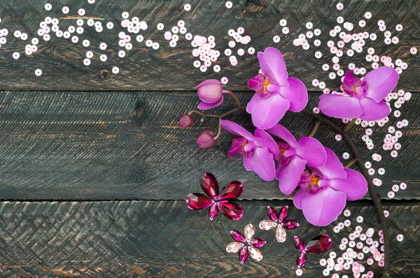 Orchid flower, crystals and sequins on the old wooden background